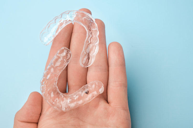 a dental patient hand holding clear aligners.