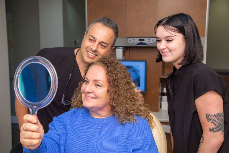 Dr. Ashkan Haeri And Staff Member Examining A Patient Who Just Got A New Smile With Dental Implants