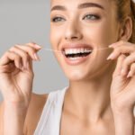 Close up photo of a woman flossing her teeth