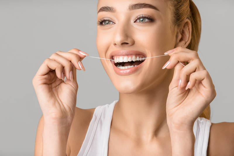 Close up photo of a woman flossing her teeth